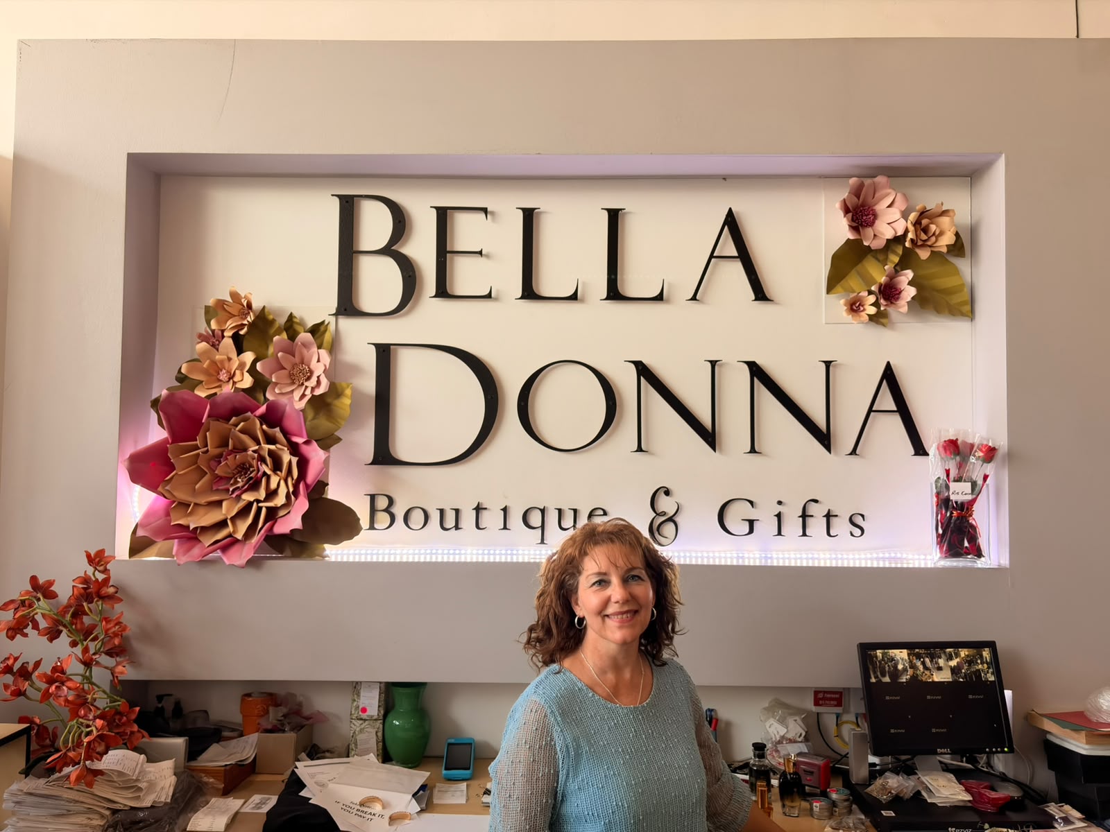 Boutique owner in front of the Bella Donna Boutique & Gifts sign